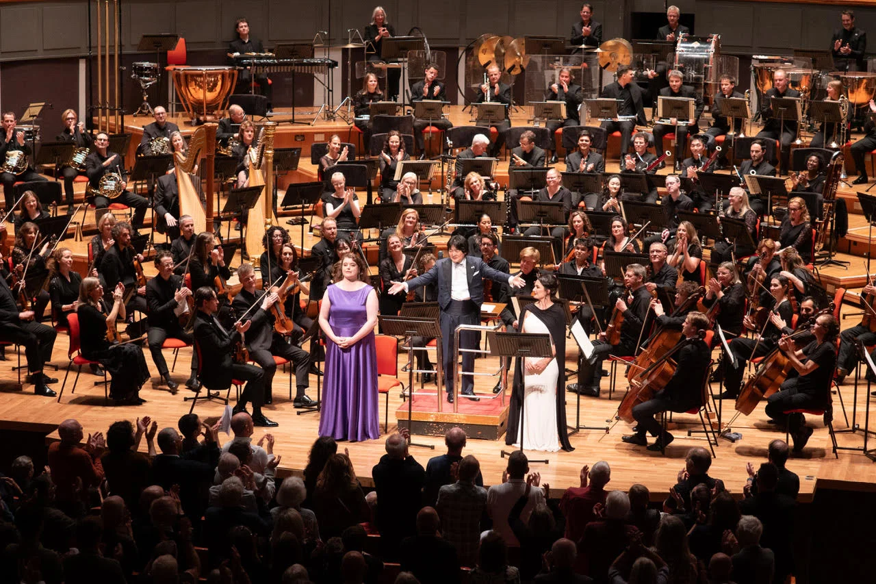 Kazuki Yamada and two vocal soloists acknowledge the audience at Symphony Hall, surrounded by applauding CBSO musicians at the season-opening concert.